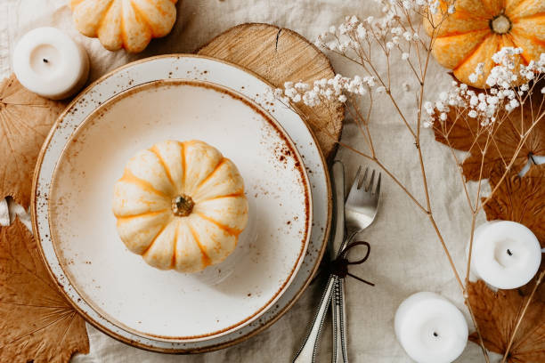 istock Top view on a decorated table setting for Thanksgiving dinner. Autumn ornate, white pumpkin on ceramic plates. 1061998796