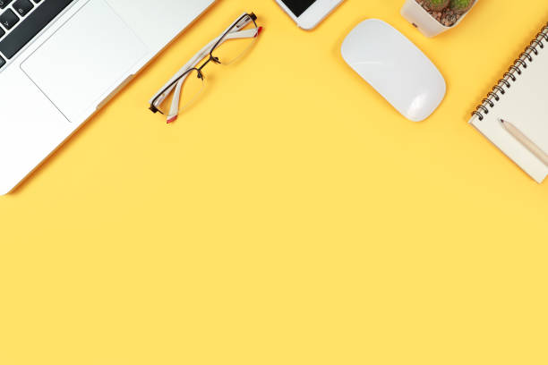 istock workspace table with laptop computer, office supplies, coffee cup, cell phone and coffee cup on yellow background 1062008394