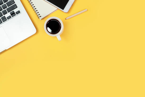 istock workspace table with laptop computer, office supplies, coffee cup, cell phone and coffee cup on yellow background 1062008408