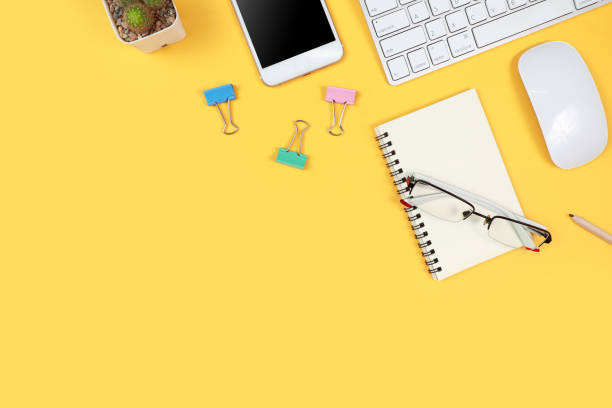 istock workspace table with laptop computer, office supplies, coffee cup, cell phone and coffee cup on yellow background 1062008436