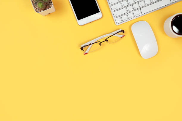 istock workspace table with laptop computer, office supplies, coffee cup, cell phone and coffee cup on yellow background 1062008448
