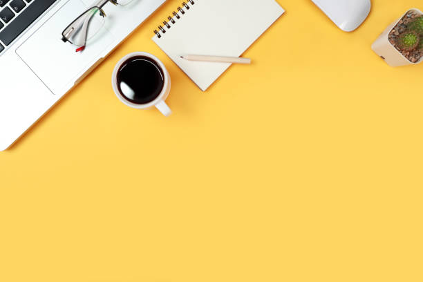 istock workspace business desk with computer, coffee cup, notebook and glasses on yellow pastel background 1062008524