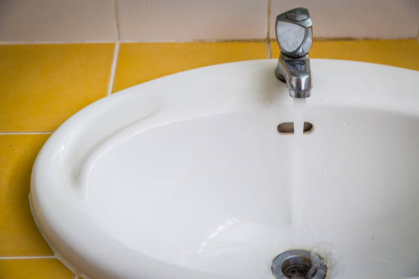 istock White wash sink in a bathroom with open the water 1062020924
