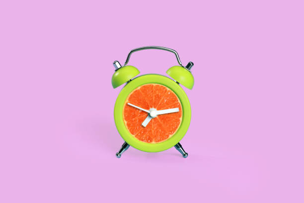 istock orange in time clock on pink pastel desk 1062033264