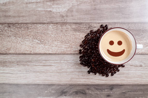 istock coffee cup with smiling face and bean on wooden table 1062033396