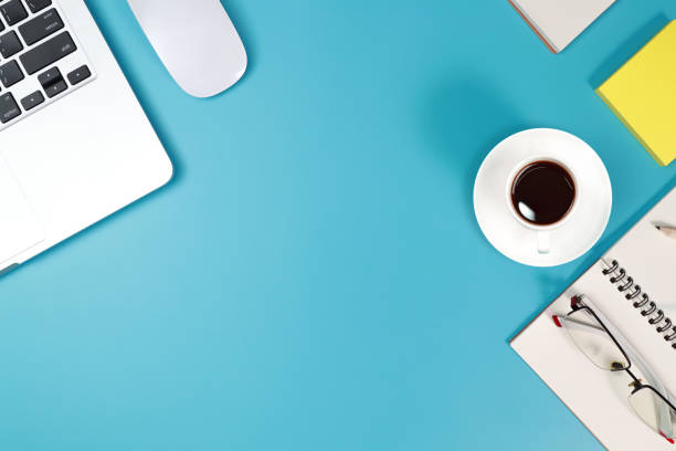 istock flat lay workspace table with laptop computer, office supplies, coffee cup, cell phone, and coffee cup on blue background 1062033462