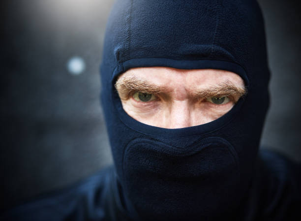 istock Man in balaclava glares at camera threateningly 1062037768