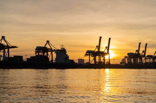 istock Container cargo ship in the export and import business and logistics international goods in urban city. Shipping cargo to the harbor by crane at sunset. 1062043554