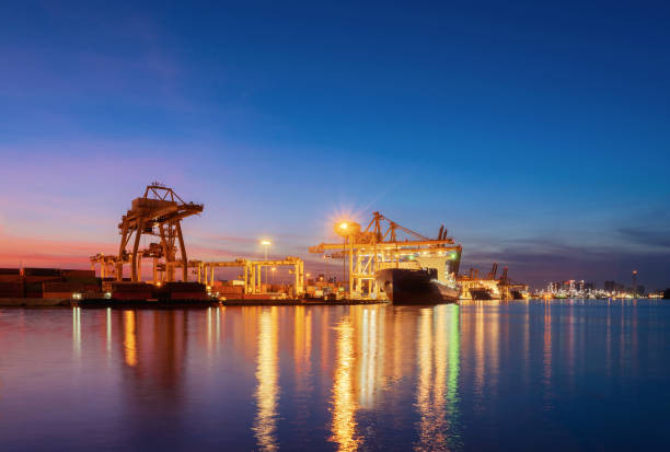 istock Container cargo ship in the export and import business and logistics international goods in urban city. Shipping cargo to the harbor by crane at sunset. 1062043808