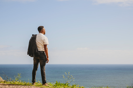 Casual man with jacket slung over his shoulder thoughtfully looking at view