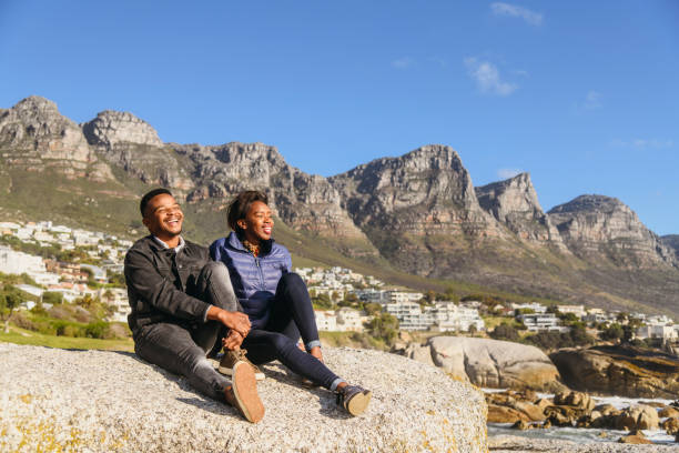 istock Happy african young couple sit on rocks together laughing 1062052770