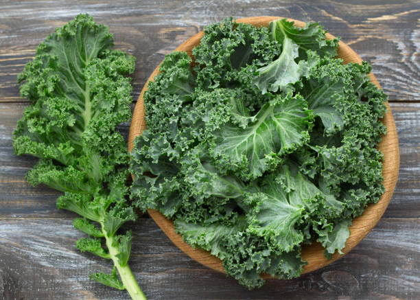 istock Fresh green curly kale leaves on a wooden table 1062059506