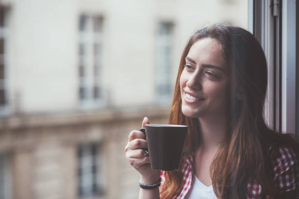 istock Relaxed woman drinking coffee at the window 1062061968