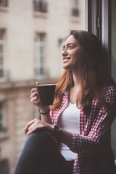 istock Relaxed woman drinking coffee at the window 1062062516