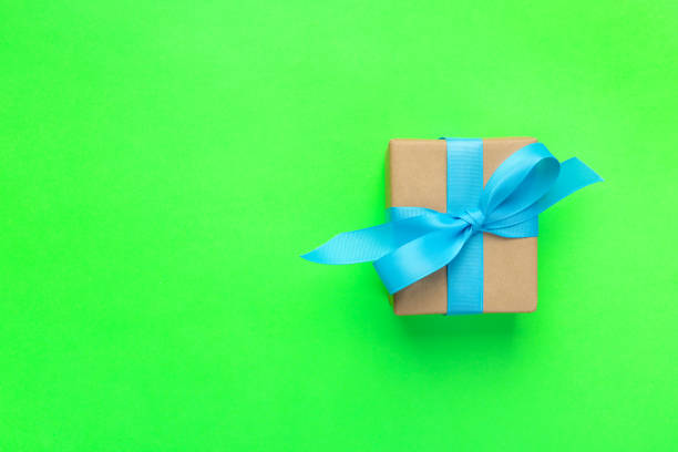 istock gift wrapped and decorated with blue bow on green background with copy space. Flat lay, top view 1062064412