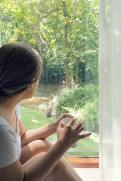istock Asian woman holding white cup looking at forest view 1062064566