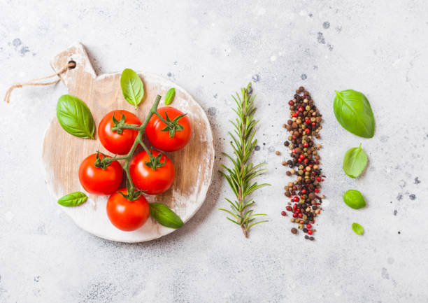 istock Organic Cherry Tomatoes on the Vine with basil and pepper on white kitchen background. Fresh rosemary 1062069558