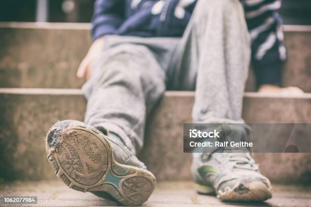 Old Broken Shoes Of A Little Boy As A Symbol For Child Poverty Stock Photo - Download Image Now