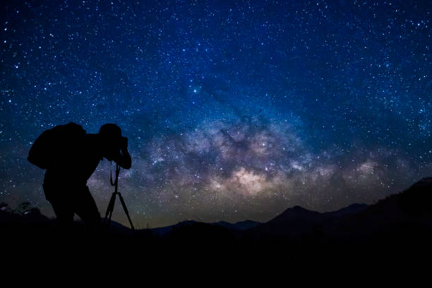 istock Photographer with starry night sky milkyway 1062078178