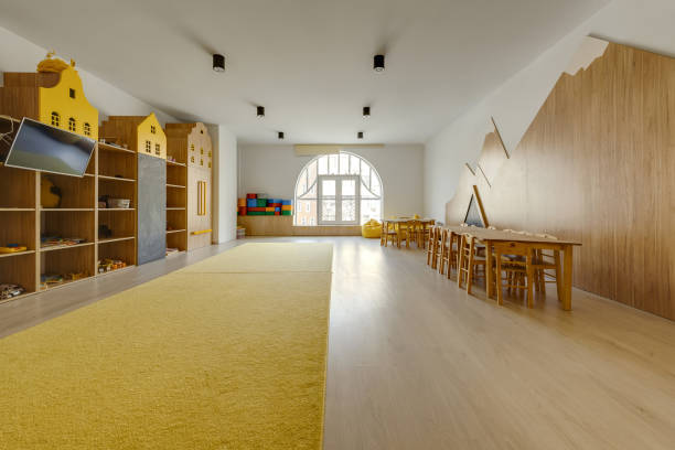 istock cozy kindergarten classroom interior with yellow carpet, tables and tv 1062087886