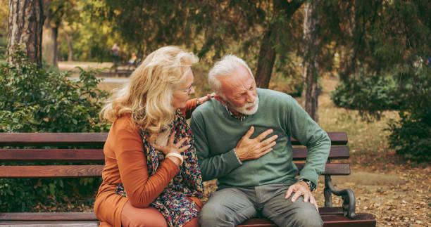 Elderly man having chest pains or heart attack in the park stock photo