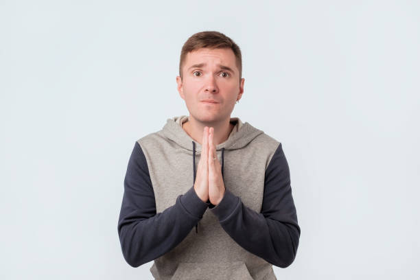 istock Handsome emotive poor guy clenching hands together over chest, frowning while begging for forgiveness 1062100628
