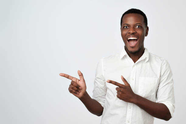 istock Handsome young african man pointing away and looking at camera with smile 1062101026