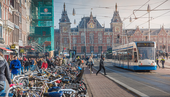 Amsterdam, Netherlands - March 29, 2018: View on Amsterdam from  street with row of shops; tram, tourists and bicycle iin Amsterdam. Amsterdam is capital of the Netherlands.