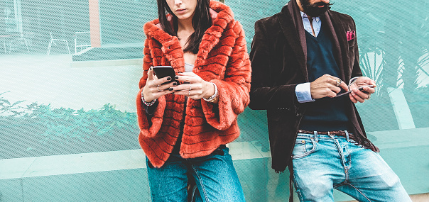 Trendy influencers people using smartphone social media app - Young fashion couple watching story video on mobile cell phone - Technology trends, marketing and new digital job concept - Focus on hands