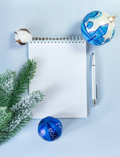 istock clean white Notepad sheet, place for writing, silver handle, green spruce branch, cotton branch, Christmas ball on blue background, top view, flat lay 1062120452