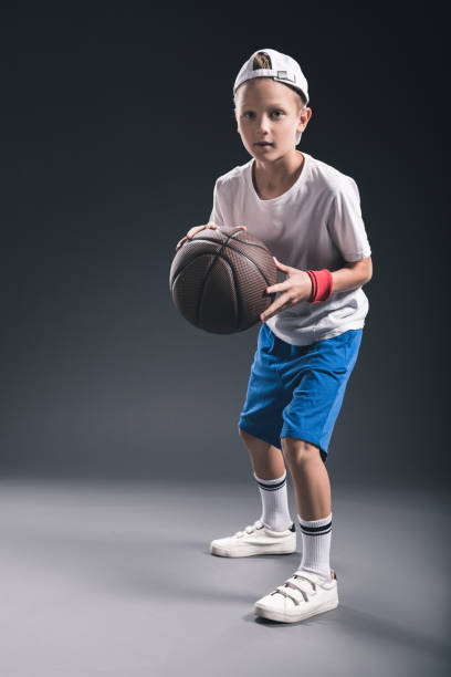 istock stylish boy playing basketball on grey background 1062125080