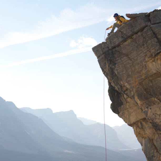 istock Male climber looks off from cliff edge 1062129382