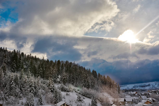horizontal shot of day in winter time, snow covering forest and village.