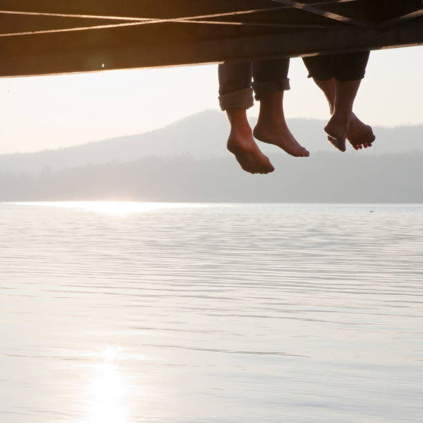istock Couple's feet dangle from lake pier at sunrise 1062136842