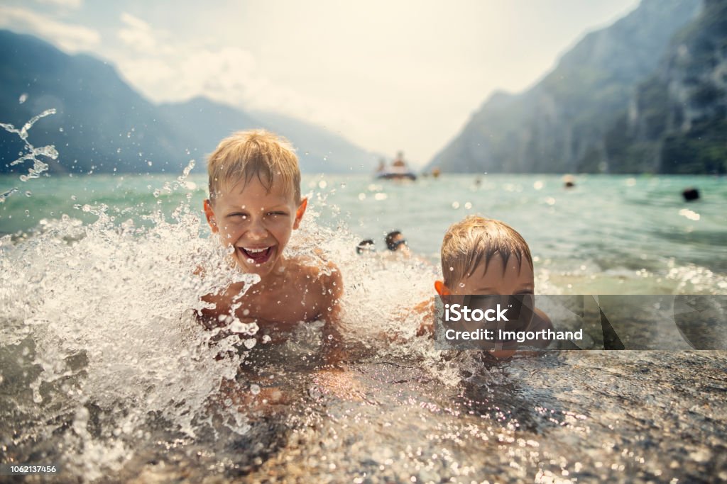 Ragazzini che sguazzano tra le onde del Lago di Garda, Italia - Foto stock royalty-free di Bambino Ragazzini che sguazzano tra le onde del Lago di Garda, Italia - Foto stock royalty-free di Bambino