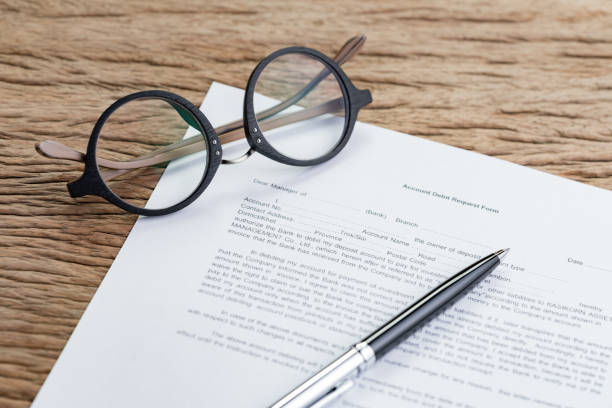 istock Bank account, debt or financial sign in concept, Account debit request form, paper work document of banking form with pen and eyeglasses on wood table, open an account for savings and investment 1062143402