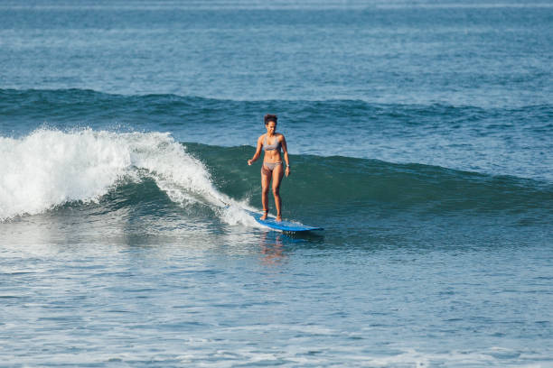 istock surfer woman riding wave on blue surfboard in Bali 1062147202