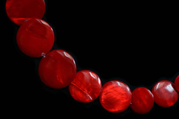Red necklace from round flat beads on a dark background close up
