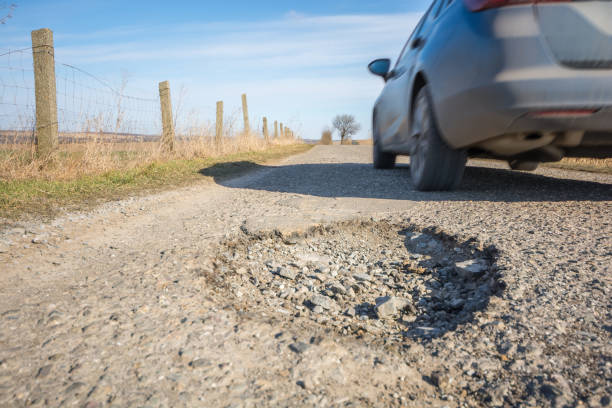 istock Big pothole on a country road with passing car 1062148876