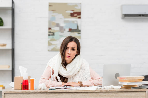 istock sick young businesswoman looking at camera while sitting at workplace 1062149810