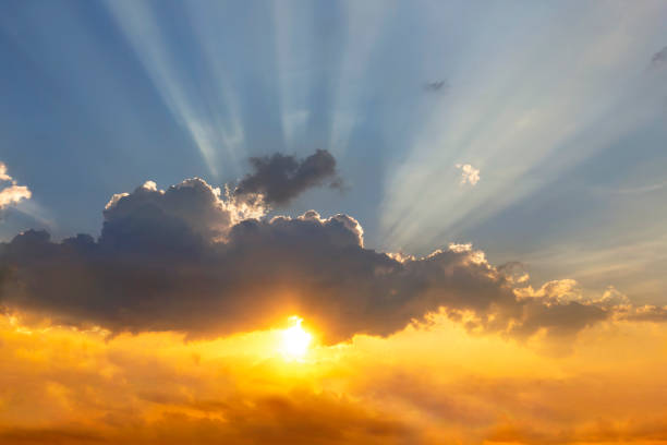 istock Clouds and sun shines through rays of light in the illuminated picturesque sky. 1062173824