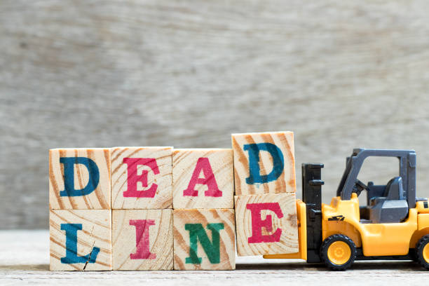 istock Toy forklift hold letter block d, e to complete word deadline on wood background 1062184334