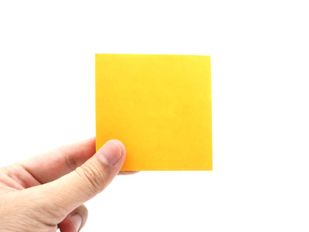 Hand holding an orange paper stick note isolated on a white background. stock photo