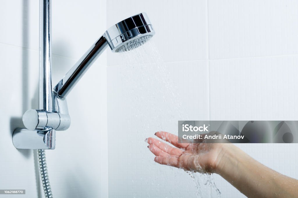 la mano de la chica alcanza para el alma de plata que se encuentra en el soporte. salpicaduras - Foto de stock de Ducha libre de derechos