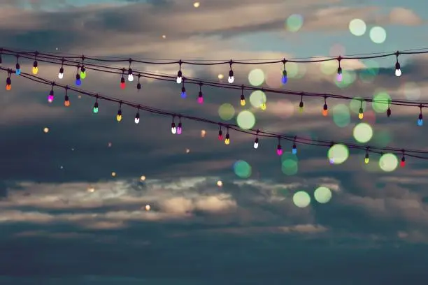 Ropes of lights painted in different colors glitter in a night sky.