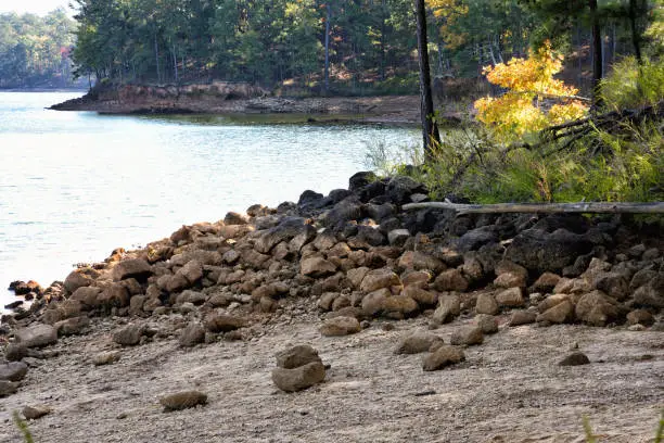 Beach filled with rocks and stones on the shore of the Etowah River at Red Top Mountain in Acworth Georgia USA. Autumn season with some slight leaf color.
