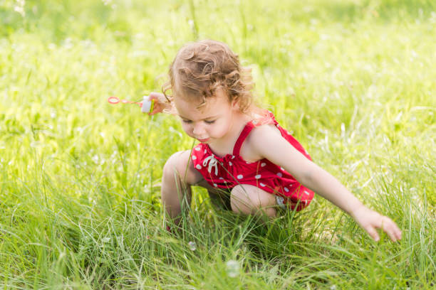 istock Little Girl Blowing Soap Bubbles In Sunny Summer Day 1062228124