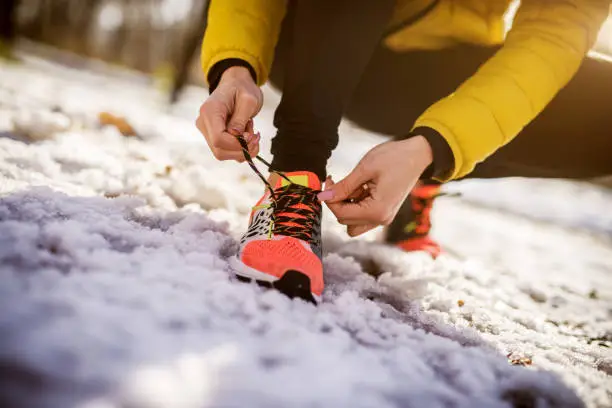 Photo of Close up of woman tying shoelace. Training in nature in winter.