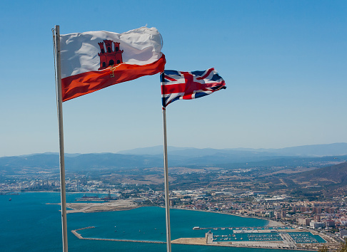 The Union Jack and the flag of Gibraltar flapping in the breeze at the top of the Rock of Gibraltar