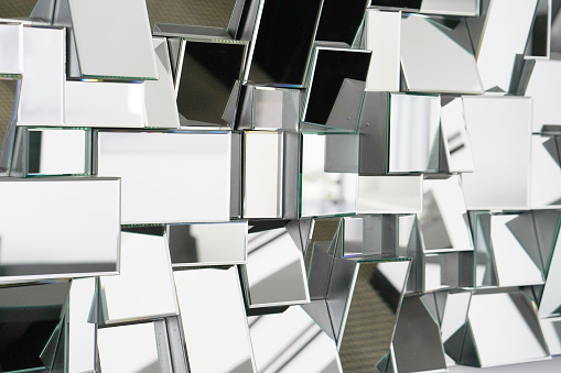 Mirror with foursquare in wall, decoration and reflection. Abstract glass background. Polygonal surface. Close-up. Texture.